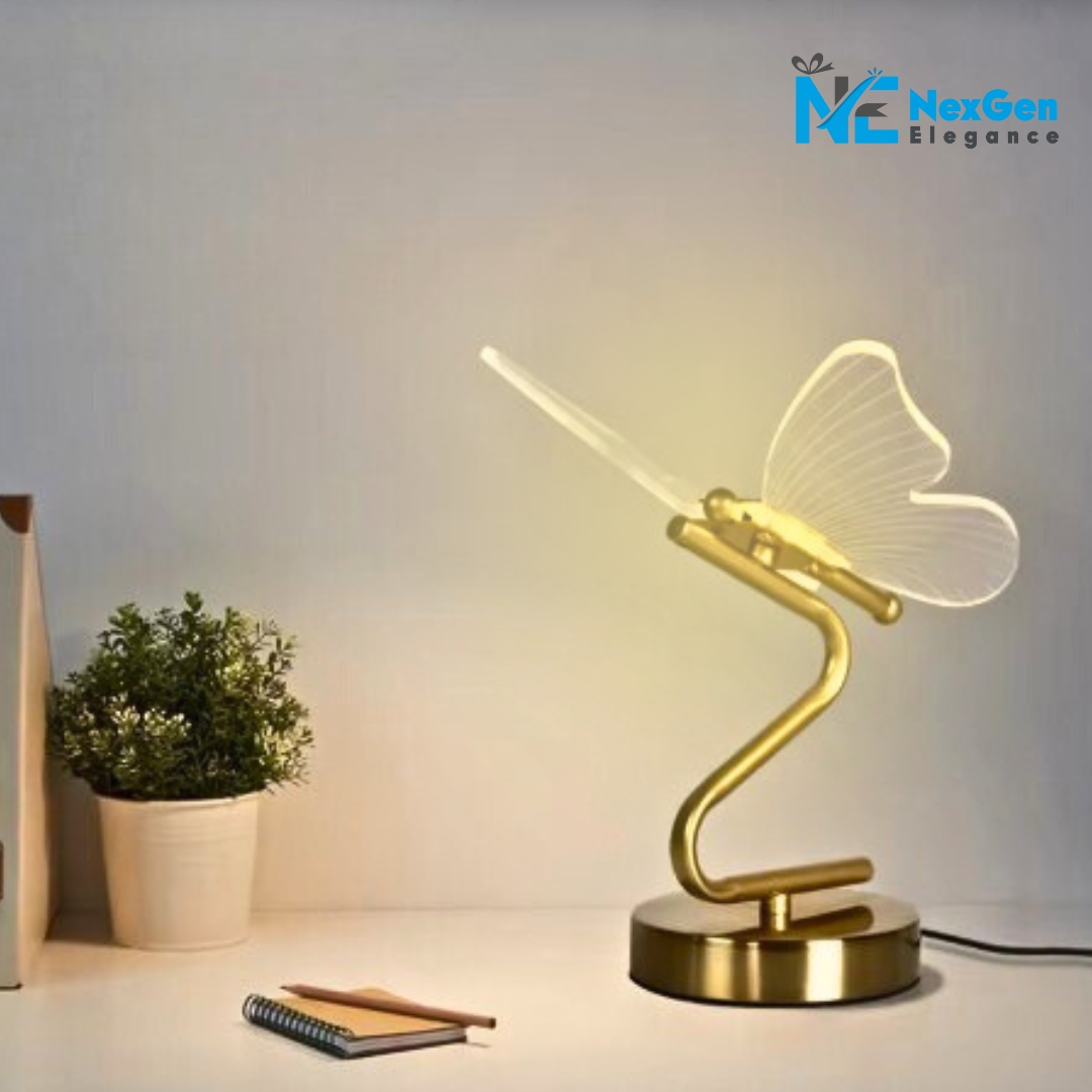 Nordic Elegant Butterfly Lamp on desk next to plant and notebook, glowing wings on curved golden base, NexGen Elegance logo top right