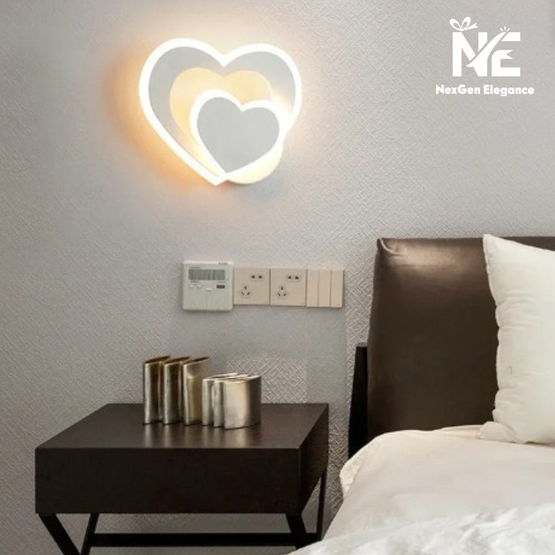 Heart Shape Wall Lamp on light gray textured wall above dark bedside table with silver décor and white bedding.