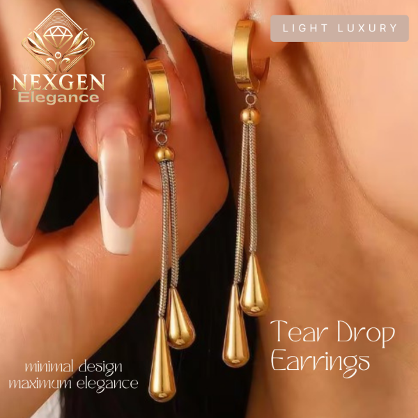 Close-up of a person's earlobe wearing a golden tear drop dangle earring, featuring a hoop top with thin chains leading to two tear drop pendants, highlighting the elegant and luxurious design.