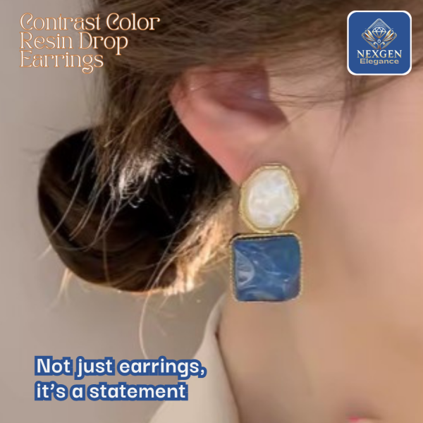 A woman is wearing a pair of drop earrings made with contrast colored resin. The earrings feature one white and one blue resin piece.