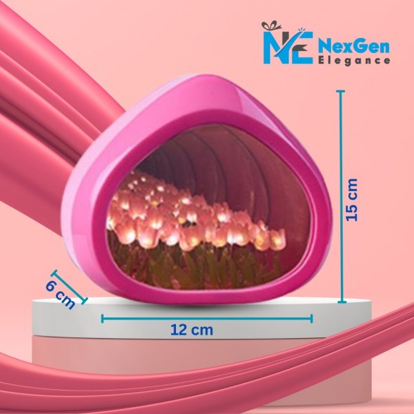 Pink droplet-shaped Love Tulip Night Light showing glowing pink and white tulip LEDs inside. Lamp dimensions: 15 cm tall, 12 cm wide, 6 cm deep. Placed on a two-tiered pink and white stand with flowing pink fabric background.